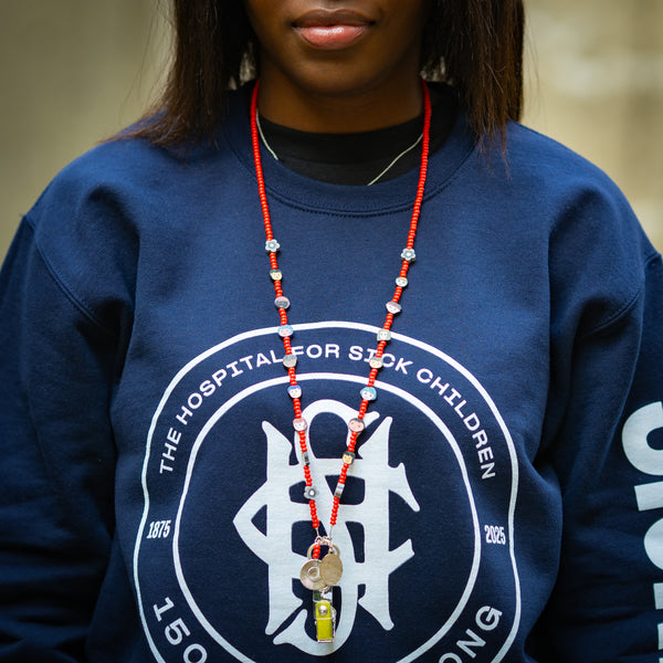 Person wearing a navy blue sweatshirt with a red beaded lanyard, standing outdoors.