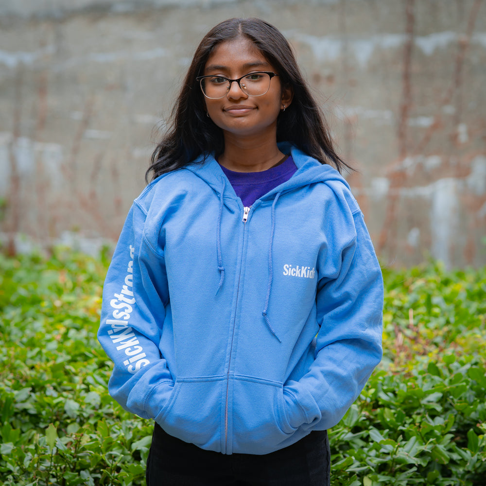 Person wearing a blue hoodie with 'Sick Kids' branding outdoors.