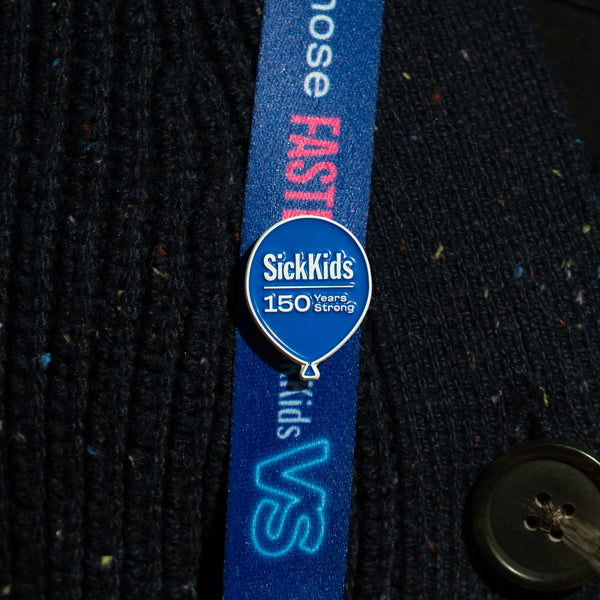 A lanyard with a blue strap and a pin badge featuring the SickKids hospital logo to celebrate their 150 years.