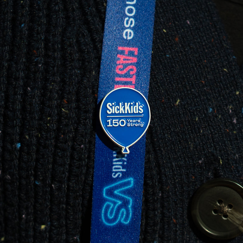 A lanyard with a blue strap and a pin badge featuring the SickKids hospital logo to celebrate their 150 years.