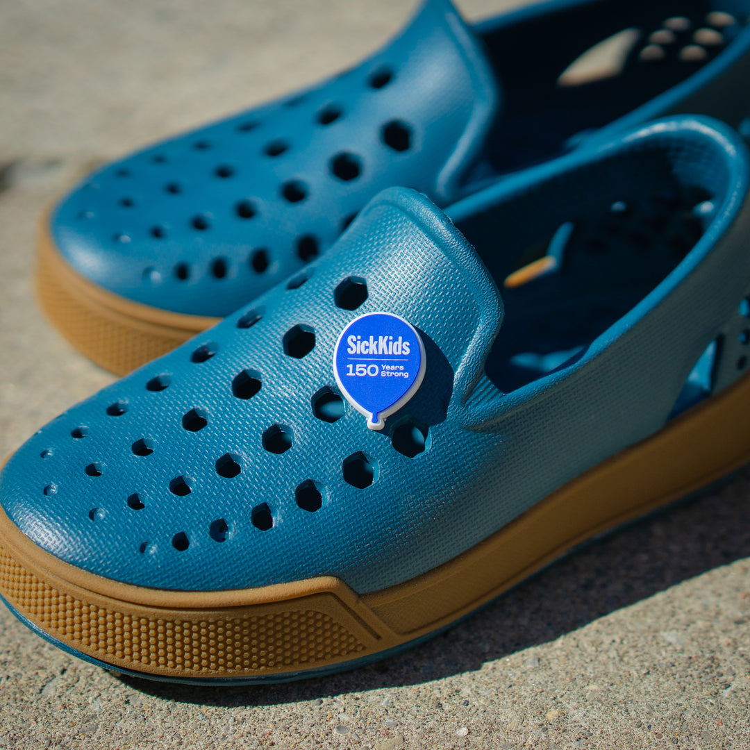 A pair of blue casual shoes with a 'SickKids 150' charm on the upper part.