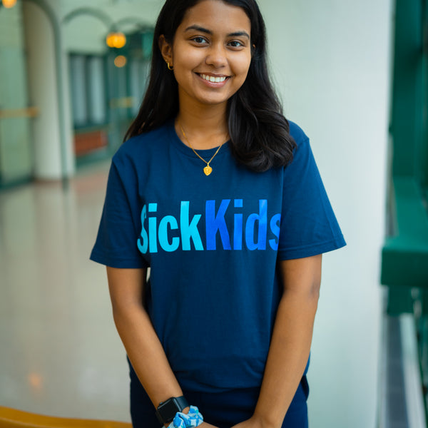 A person wearing a navy blue t-shirt with the text 'SickKids' in blue font.