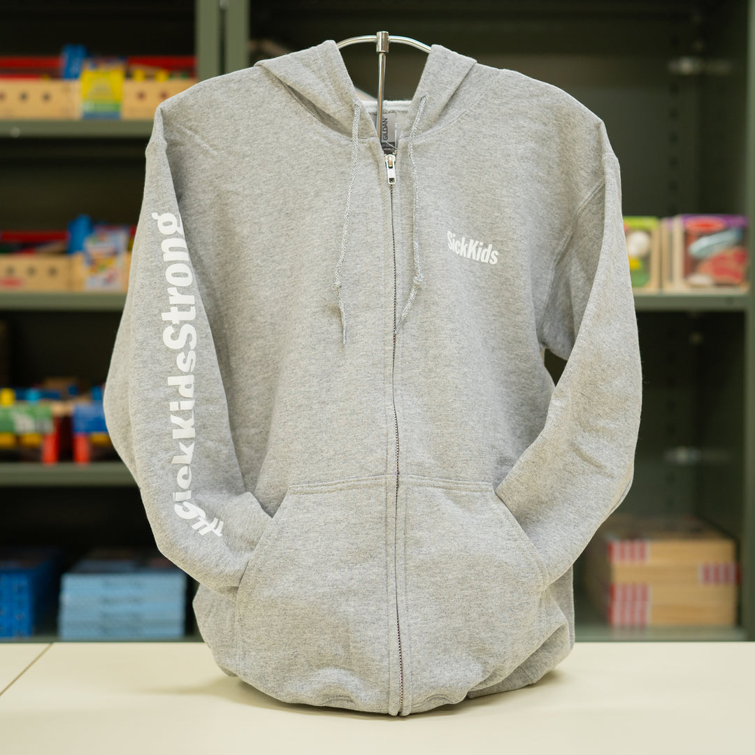 A light grey SickKids full-zip hoodie with the brand's name on the front and sleeve, displayed on a stand.