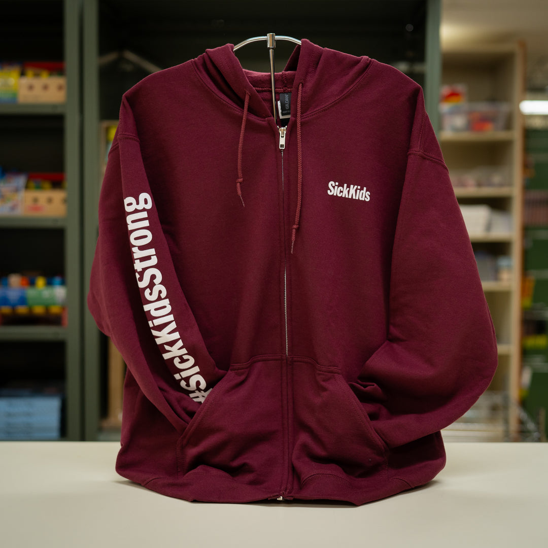 A maroon SickKids full-zip hoodie with the brand's name on the front and sleeve, displayed on a stand.