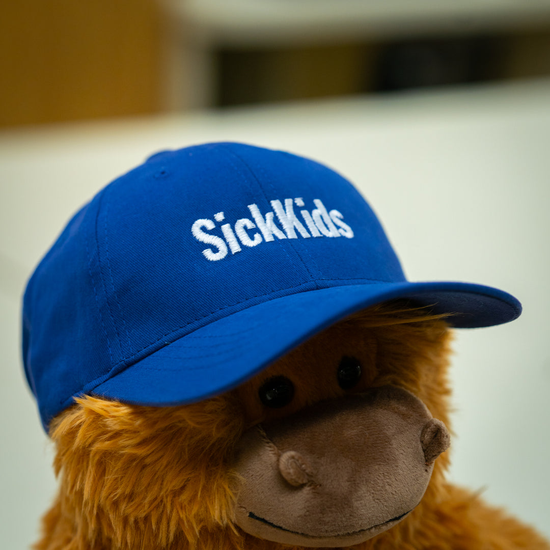 A youth baseball cap in royal blue color with the logo 'SickKids' displayed on the front.
