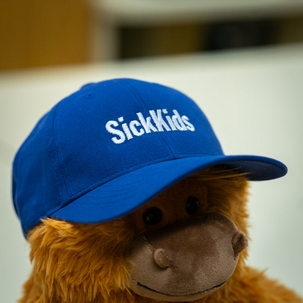 A youth baseball cap in royal blue color with the logo 'SickKids' displayed on the front.
