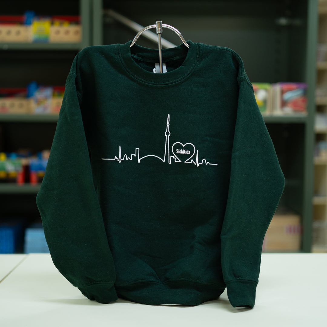 A green youth crewneck sweater with a graphic print of a skyline and a heart shape on the front.