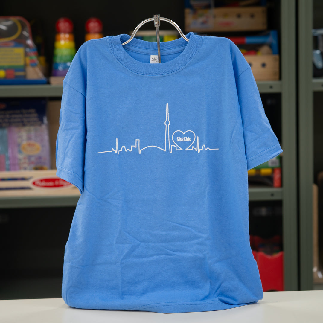 Blue t-shirt with a white skyline design on a hanger against a blurred classroom background