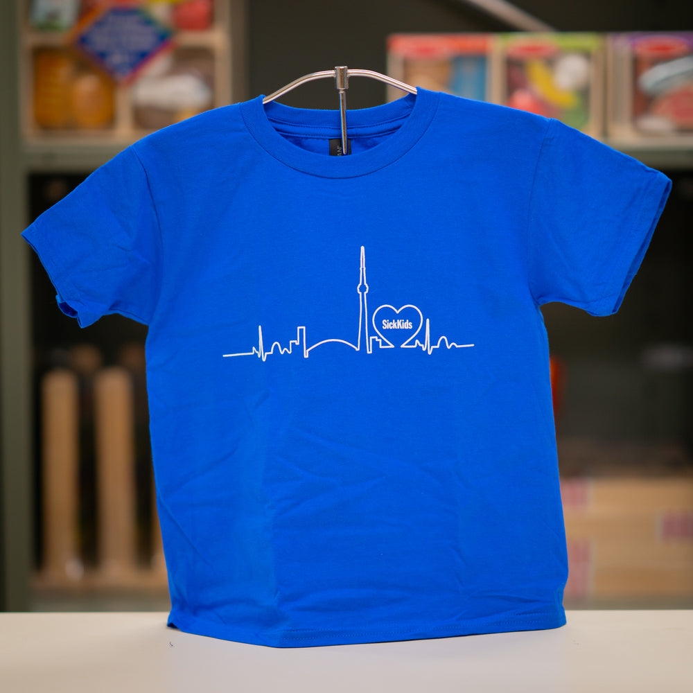 A blue youth T-shirt with a skyline logo on the front, displaying a heartbeat line and the SickKids logo.