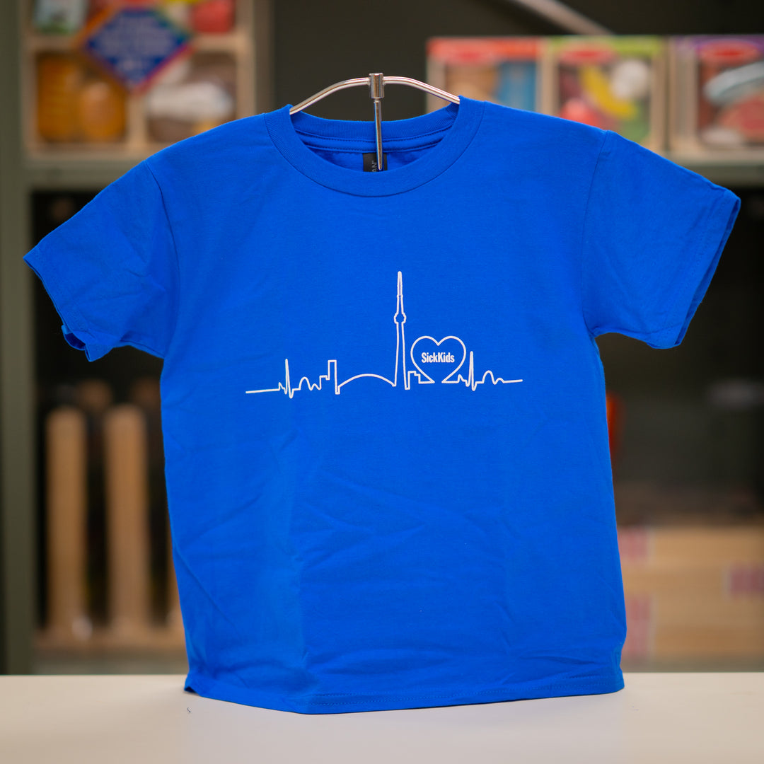 A blue youth T-shirt with a skyline logo on the front, displaying a heartbeat line and the SickKids logo.